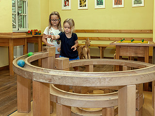 Das Bild zeigt zwei Mädchen, die mit einer Kugelbahn im Spielzimmer des Hunsrücker Holzmuseums spielen.