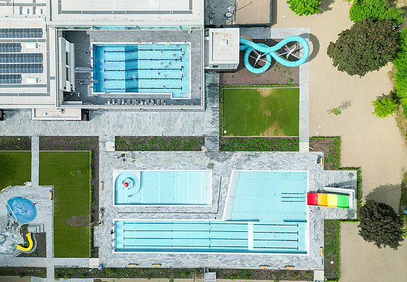 Das Foto zeigt die Gesamtanlage des Vitteliusbad Wittlich, mit Hallenbad, Freibad, Rutschen, Liegewiesen und Kinderbereich.